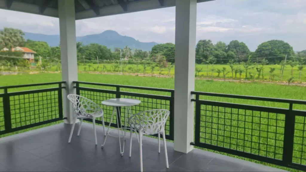 Modern villa balcony with mountain views in Kampot, featuring designer outdoor furniture and panoramic views of rice paddies