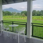 Modern villa balcony with mountain views in Kampot, featuring designer outdoor furniture and panoramic views of rice paddies