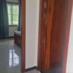 Interior hallway with polished tile floors, wooden doors and bedroom entrance showing blue curtains